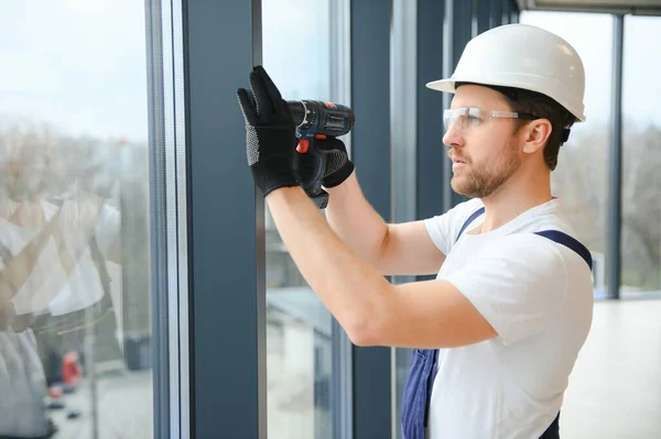 在新的房屋建筑工地安装窗玻璃的英俊年轻人 — 图库照片
