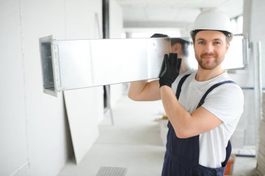 Alüminyum İskeledeki Profesyonel HVAC İşçisi Yeni Yapılmış Ticari Binanın içine Hava Kanalı Kuruyor. Endüstriyel Tema.