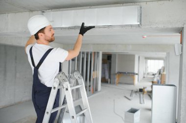 Alüminyum İskeledeki Profesyonel HVAC İşçisi Yeni Yapılmış Ticari Binanın içine Hava Kanalı Kuruyor. Endüstriyel Tema.