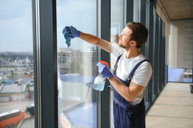 Profesyonel bir temizlik şirketinin çalışanı binanın camlarını yıkıyor. Dükkan ve işletmeler için vitrin temizliği