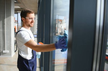 Profesyonel bir temizlik şirketinin çalışanı binanın camlarını yıkıyor. Dükkan ve işletmeler için vitrin temizliği
