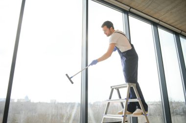 Profesyonel bir temizlik şirketinin çalışanı binanın camlarını yıkıyor. Dükkan ve işletmeler için vitrin temizliği