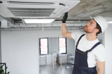 Yakışıklı genç elektrikçi bir müşteri evine klima kuruyor.