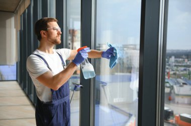 Profesyonel bir temizlik şirketinin çalışanı binanın camlarını yıkıyor. Dükkan ve işletmeler için vitrin temizliği