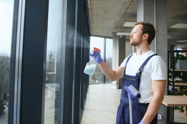 Profesyonel bir temizlik şirketinin çalışanı binanın camlarını yıkıyor. Dükkan ve işletmeler için vitrin temizliği