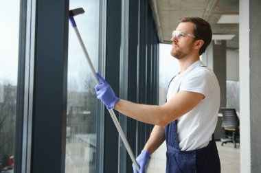 Profesyonel bir temizlik şirketinin çalışanı binanın camlarını yıkıyor. Dükkan ve işletmeler için vitrin temizliği