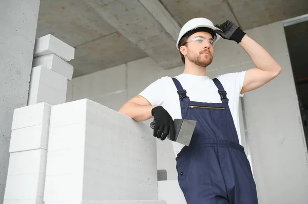 stock image Portrait of a young foreman in uniform standing on a construction site indoors near a stepladder