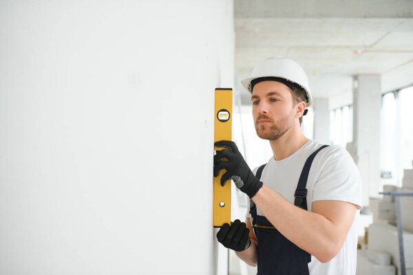 Portrait of positive, handsome young male builder in hard hat