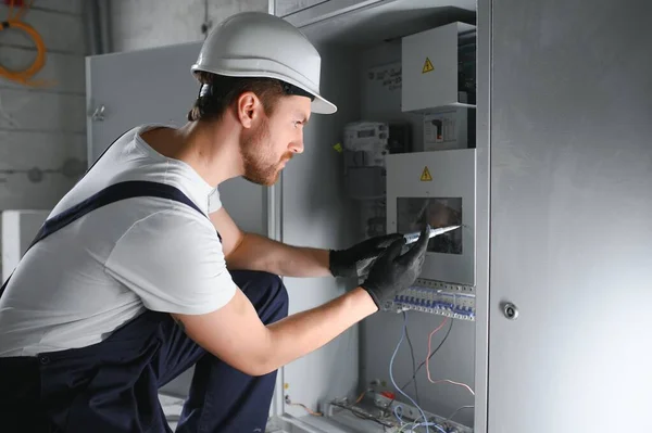 Man, an electrical technician working in a switchboard with fuses. Installation and connection of electrical equipment. Professional with tools in hand. concept of complex work, space for text