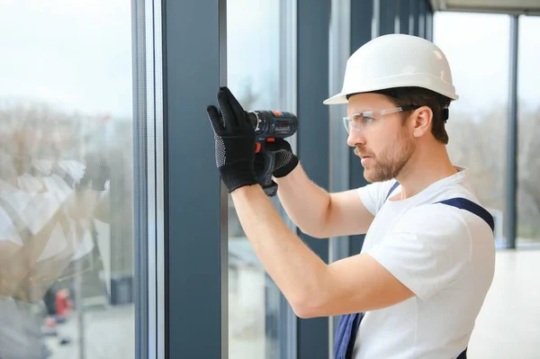 在新的房屋建筑工地安装窗玻璃的英俊年轻人 — 图库照片