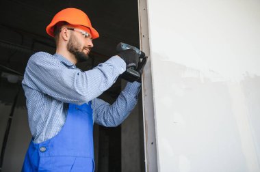 İşçiler alçıdan bir duvar örüyor