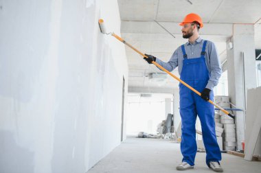 Boyacı duvarı boyuyor, boya silindiriyle..