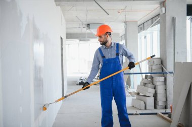 Boyacı duvarı boyuyor, boya silindiriyle..