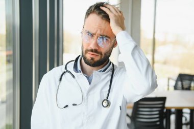 Stressed male doctor. Mid adult male doctor working long hours. Overworked doctor in his office. Not even doctors are exempt from burnout.