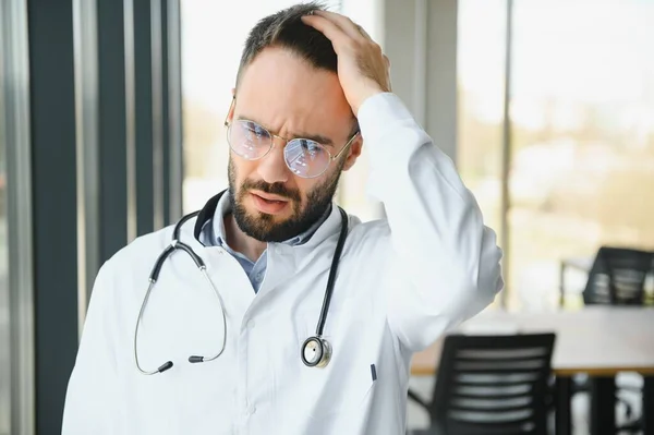 stock image Stressed male doctor. Mid adult male doctor working long hours. Overworked doctor in his office. Not even doctors are exempt from burnout.