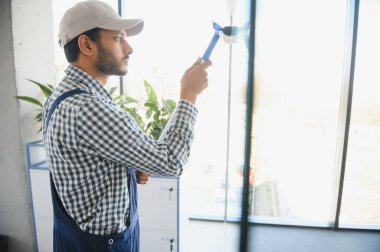 Ofisin camlarını silen genç Hintli adam.