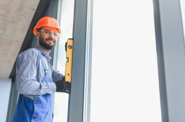 Evdeki oturma odasına plastik pencereler monte eden ya da ayarlayan işçi.