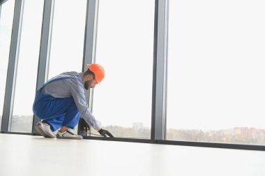 Evdeki oturma odasına plastik pencereler monte eden ya da ayarlayan işçi.