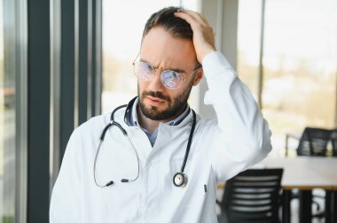 Stressed male doctor. Mid adult male doctor working long hours. Overworked doctor in his office. Not even doctors are exempt from burnout.