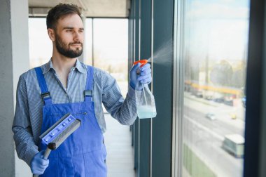 Erkek profesyonel temizlik işçisi özel ekipmanlı bir mağazanın camlarını ve pencerelerini temizliyor..