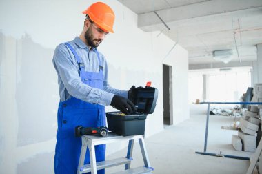 Bina, koruyucu teçhizat ve insan konsepti - inşaat alanında alet çantası taşıyan inşaatçı.