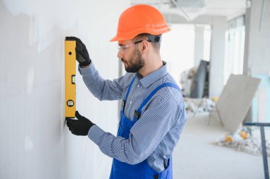 Mavi üniformalı, ruh seviyeli inşaat işçisi..