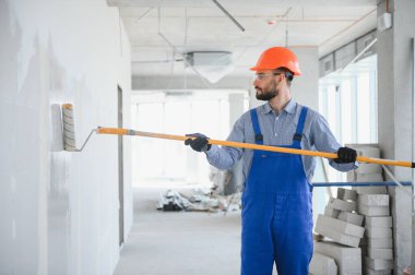 Boyacı duvarı boyuyor, boya silindiriyle..