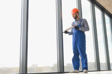 Evdeki oturma odasına plastik pencereler monte eden ya da ayarlayan işçi.