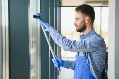 Ofisin penceresini temizleyen genç adam..