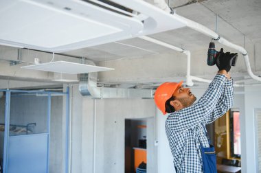 Yoğunlaşmış genç Hintli mühendis klima kuruyor.