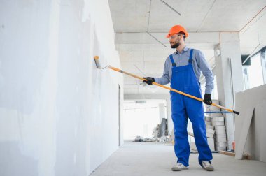 Boyacı duvarı boyuyor, boya silindiriyle..