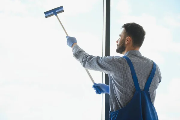 身穿工作服的男性专业清洁员用专用设备清扫商店的橱窗和橱窗 — 图库照片
