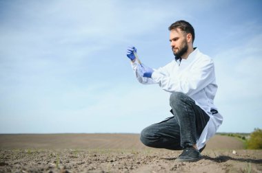 Agronomist tarladaki toprak örneklerini inceliyor.