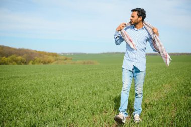 Daha az endişelenen Hintli çiftçi sağlıklı buğday tarlasında duruyor..