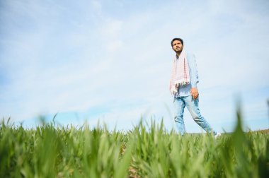 Yeşil çeltik tarlasında resmi elbise giyen genç Hintli çiftçinin portresi.