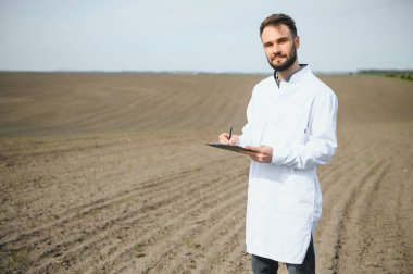 Agronomist tarladaki toprak örneklerini inceliyor.