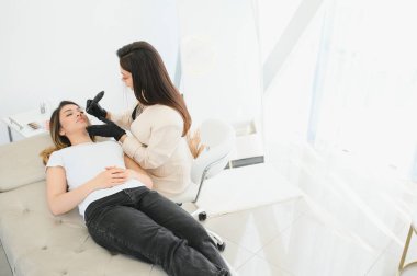 Kalıcı kaş makyajı sırasında genç bir kadın..