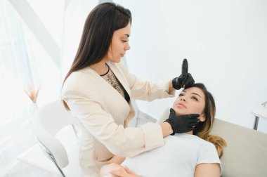 Kozmetik uzmanı kaşlarına kalıcı makyaj uyguluyor..