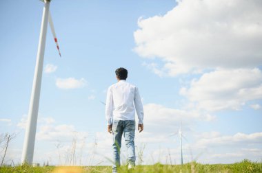 Elektrik üretmek için yel değirmeni çiftliğinde çalışan Hindistan mühendisi, rüzgar türbini çiftliğinde çalışan Asyalı adam, temiz ve yeşil enerji