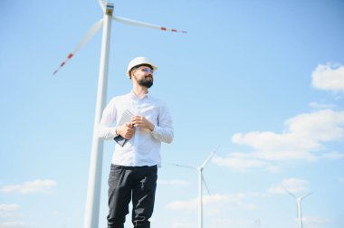 Mühendis rüzgar türbinindeki enerji üretimini kontrol ediyor. Yel değirmenleri parkında çalışan bir işçi.