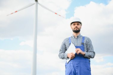 Yel değirmeni tarlasında rüzgar türbinlerinin denetimi veya bakımı için çalışan erkek mühendis.