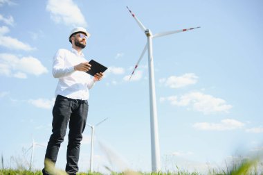 Mühendis rüzgar türbinindeki enerji üretimini kontrol ediyor. Yel değirmenleri parkında çalışan bir işçi.