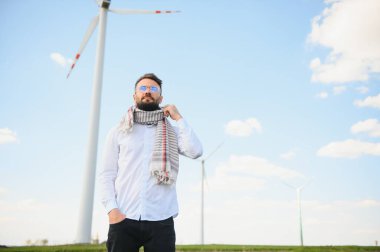 Arap adam dağda rüzgar türbiniyle dikiliyor.