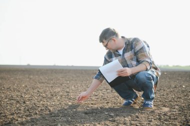 Erkek eller sahada toprağa dokunuyor. Bitki veya bitki tohumu yetiştirmeden önce toprak sağlığını kontrol eden bir çiftçi eli. İş ya da ekoloji kavramı.