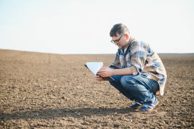 Bir çiftçi baharda ekilen bir tarlada çalışır. Sonbaharda tarlada sürülen tarlaları değerlendiren bir tarım uzmanı. Tarım. Akıllı tarım teknolojileri