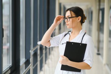 Kadın doktor hastanede dosyayla bekliyor.