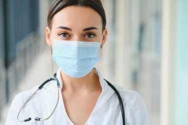Üniforma ve koruyucu maske takan genç, güzel bir kadın doktor portresi..