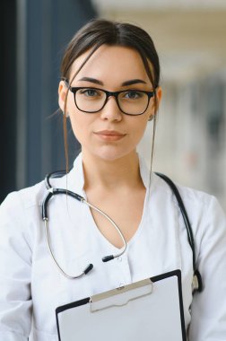 Kadın doktor hastanede dosyayla bekliyor.