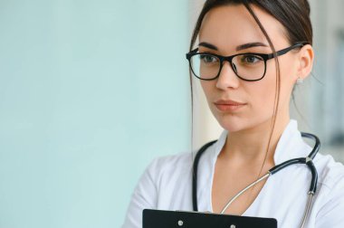 Hastane koridorunda duran genç bayan doktorun portresi. Beyaz kadın huzurevinde çalışıyor.