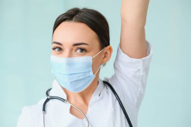 Üniforma ve koruyucu maske takan genç, güzel bir kadın doktor portresi..